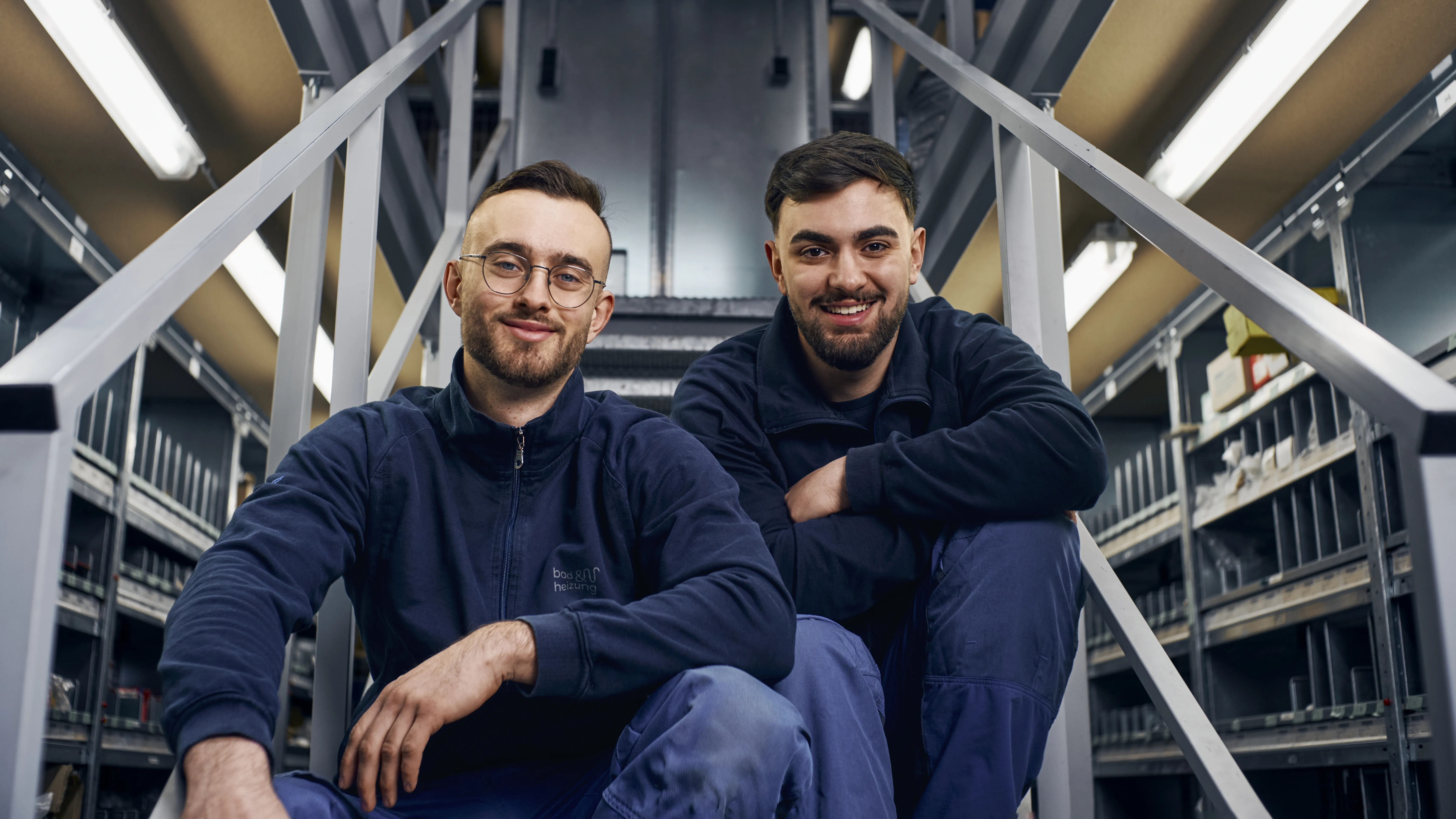 Zwei Auszubildene Anlagemechaniker (SHK) sitzen auf einer Treppe