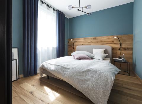 Blaues Schlafzimmer mit Holzboden und weißer Bettwäsche.