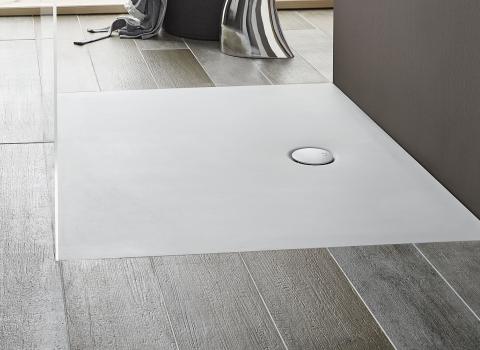 Nahaufnahme einer flachen Acryl-Duschwanne, eingebettet in ein Badezimmer mit grauen, holzstrukturierten Fliesen. Minimalistisches und modernes Design.