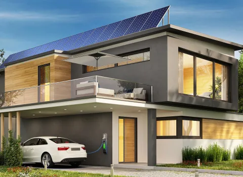 Ein modernes, zweistöckiges Haus mit Solarzellen auf dem Dach und einer Ladestation für Elektroautos.