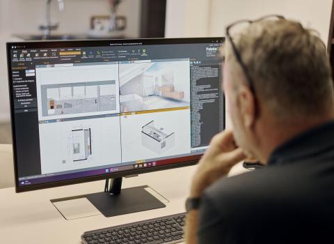 Ein Badplaner betrachtet auf einem Computerbildschirm detaillierte 3D-Modelle und Grundrisse eines Badezimmers. Er arbeitet an der digitalen Planung zur optimalen Beratung.