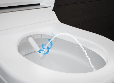 Nahaufnahme eines Dusch-WC-Aufsatzes Geberit AquaClean Tuma mit aktivierter Wasserstrahl-Funktion. Die Düse sprüht einen gezielten Wasserstrahl für optimale Reinigung.