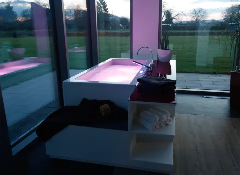 Eine beleuchtete Badewanne mit Whirlpool-Funktion steht in der Ausstellung von Issler in Grenzach-Wyhlen vor bodentiefen Fenstern.