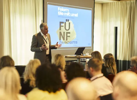 In einem Konferenzraum spricht ein Mann während eines Vortrags vor Mitgliedern der bad und heizung concept AG.