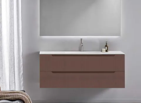 Wandhängendes Badmöbel mit geriffelter Front in Terracotta und großem beleuchtetem Spiegel.