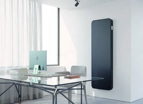 Vertikaler schwarzer Designheizkörper Relax Hybrid im modernen Büro.