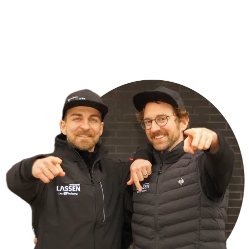 Die Geschäftsführer Konrad und Moritz Wangart stehen in schwarzer Outdoor-Kleidung nebeneinander und zeigen direkt in die Kamera.