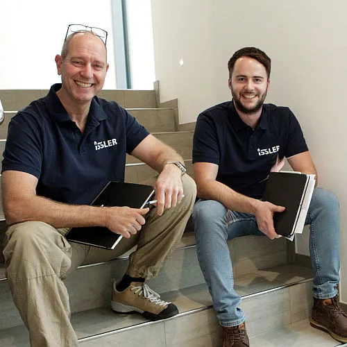 Geschäftsleitung Gerhard Wilschütz und Hannes Rütschlin sitzen auf der Treppe.