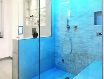 Ein modernes, offenes Badezimmer mit einer begehbaren Dusche, die in einem blauen Licht beleuchtet ist.