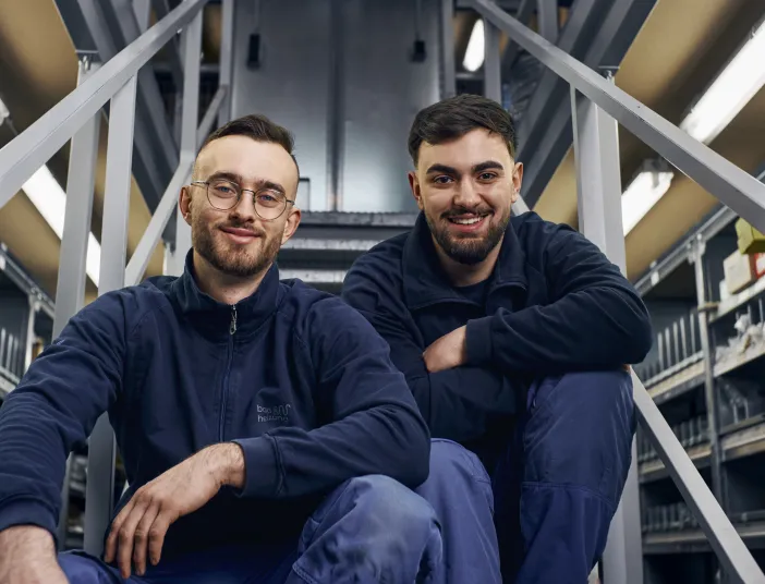 Zwei Auszubildene Anlagemechaniker (SHK) sitzen auf einer Treppe