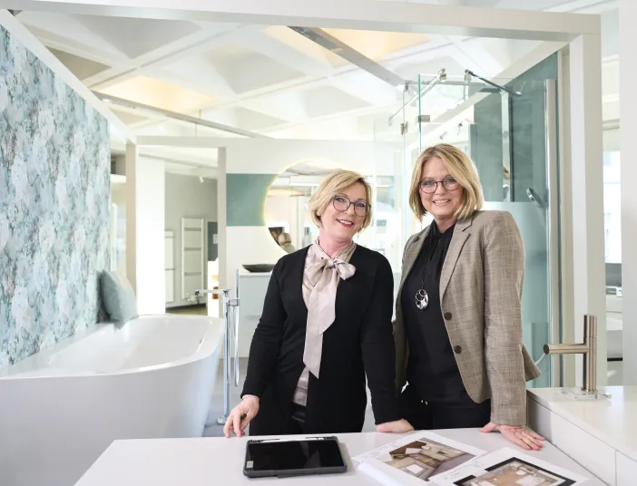 ZweiBadplanerinnen in der Bad-Ausstellung eines SHK-Handwerksbetriebes.