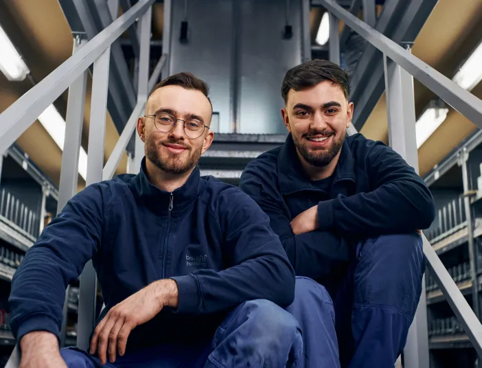 Zwei Anlagenmechaniker sitzen auf einer Treppe.