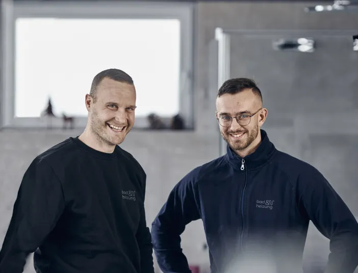 Zwei lachende Azubis von bad & heizung in einem Bad.