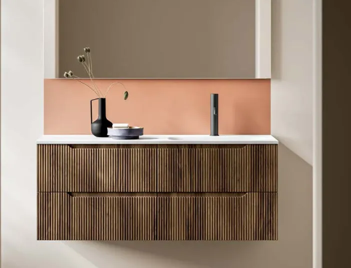 Stocco Badmöbel mit geriffelter Holzfront vor terrakottafarbener Wand und minimalistischem Spiegel.