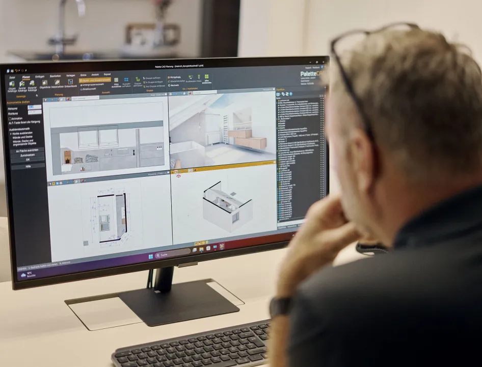 Ein Badplaner betrachtet auf einem Computerbildschirm detaillierte 3D-Modelle und Grundrisse eines Badezimmers. Er arbeitet an der digitalen Planung zur optimalen Beratung.
